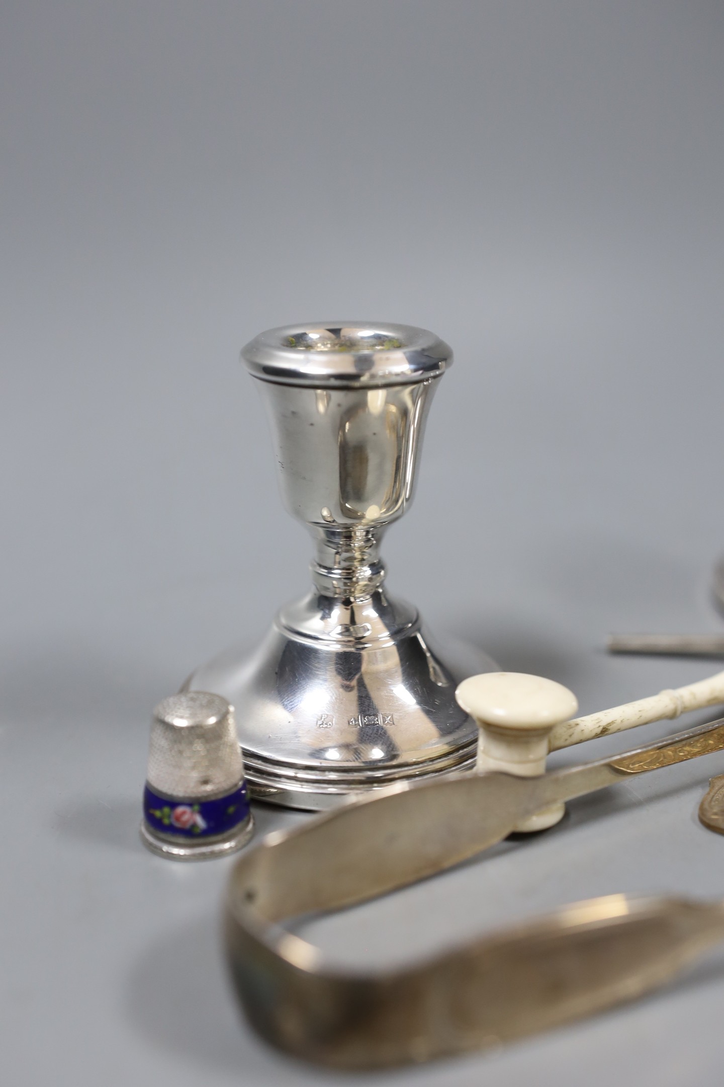 A group of mixed silver, to include sugar tongs, a pair of candlesticks, an Indian silver enamel mirror, a miniature bone gavel and other items